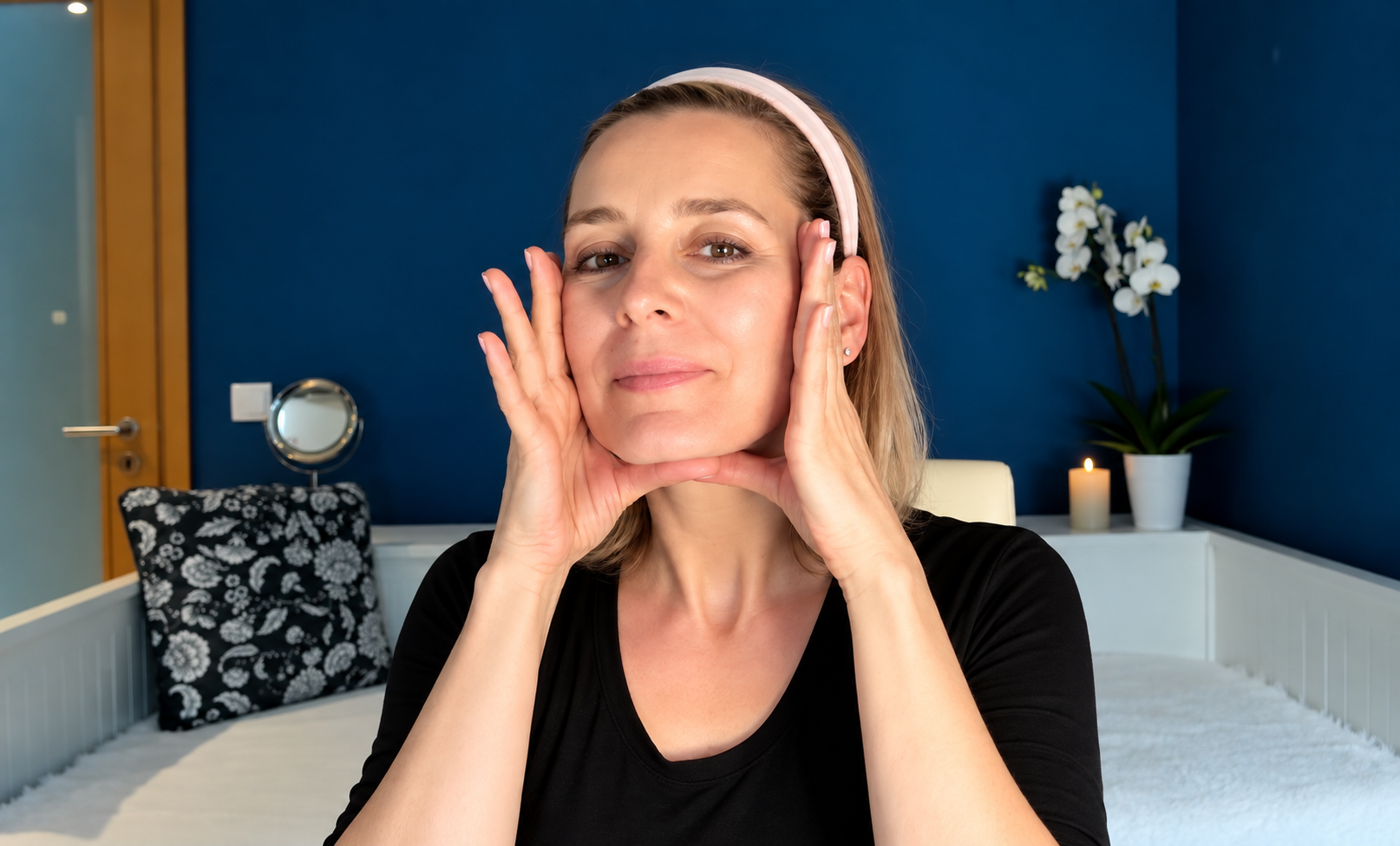 Žena provádí liftingovou masáž obličeje podél tváří a čelisti